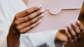 Eine Frau hält einen Umschlag mit einem VHS-Gutschein in den Händen